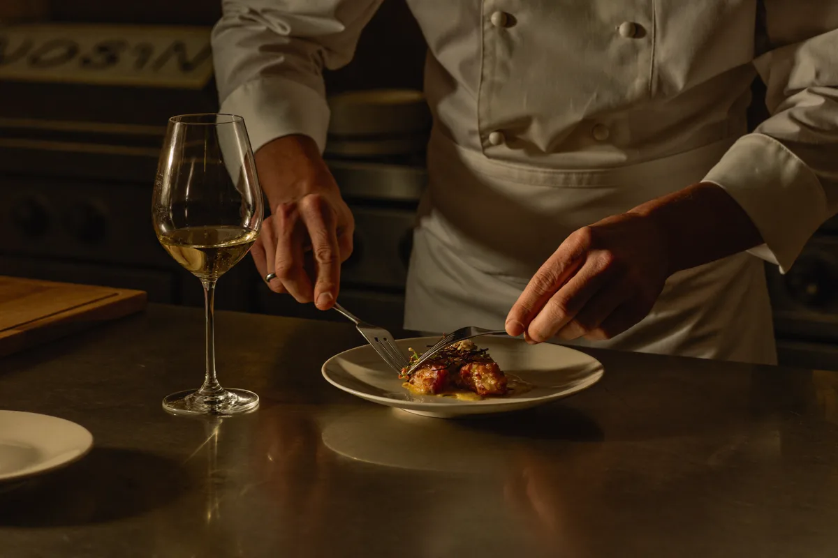 Un chef de partie dresse une assiette en cuisine